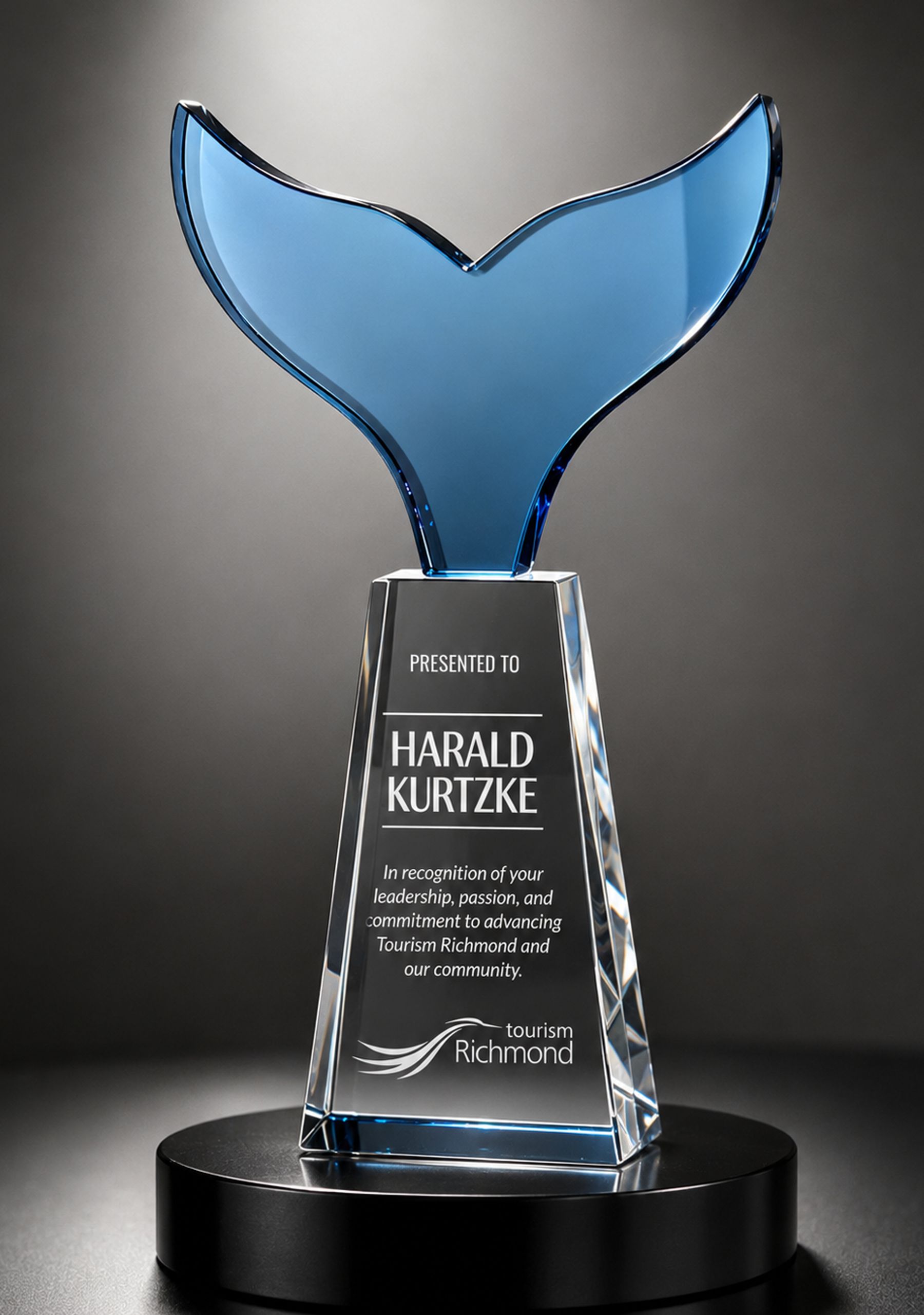 Blue glass whale tail rising from clear crystal base with engraved plate